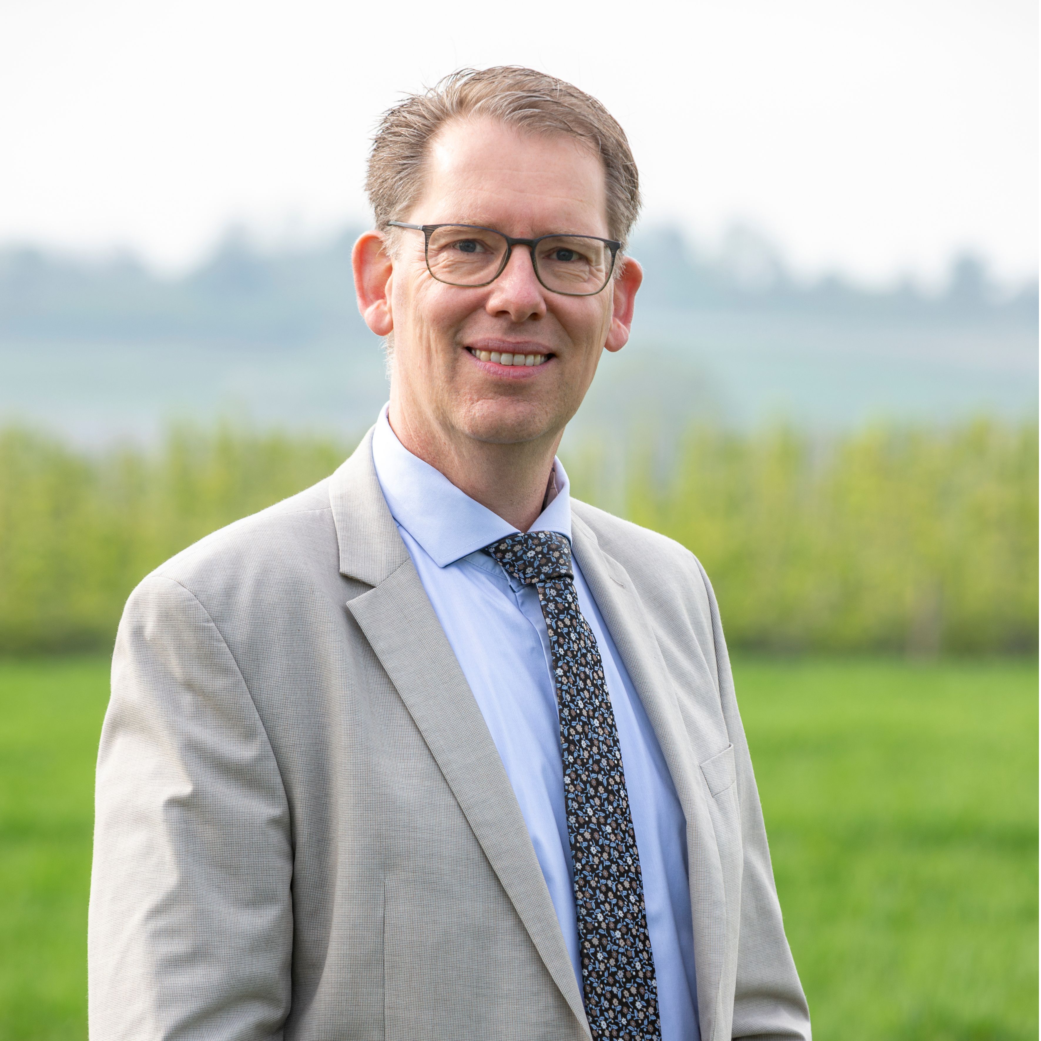 Wethouder Mark Gerritsen staat naast een elektrische auto met de laadkabel in zijn handen. 